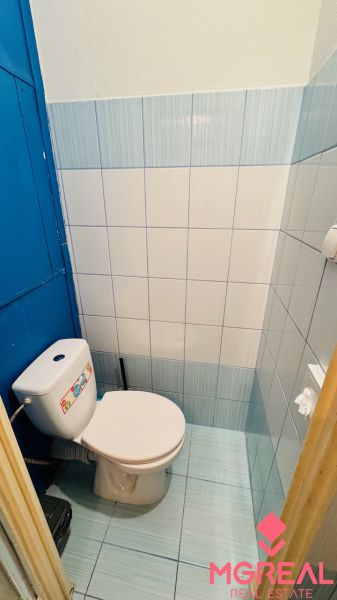 Badezimmer in einer Einzimmerwohnung mit blauen Fliesen und Toilette.