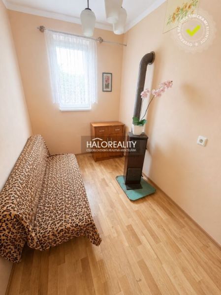 Ein Zimmer in einem Einfamilienhaus mit einem Boden in Holzoptik, einem Sofa und einem Kachelofen.