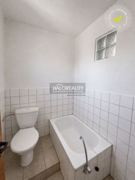 Badezimmer im Einfamilienhaus mit Badewanne, Toilette und weißen Fliesen.