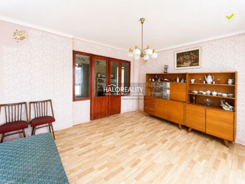 Wohnzimmer in einem Einfamilienhaus mit Retro-Möbeln und einem Boden in Holzoptik.