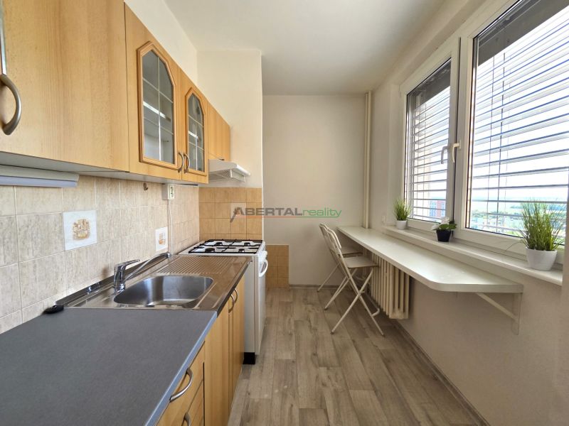 Küche in einer Einzimmerwohnung mit Holzboden und weißen Möbeln.