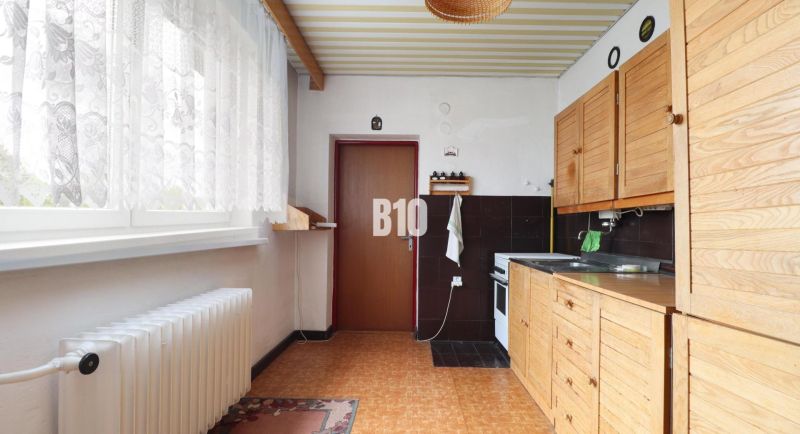 Küche in einem Einfamilienhaus mit Holzdekor und weißen Vorhängen.