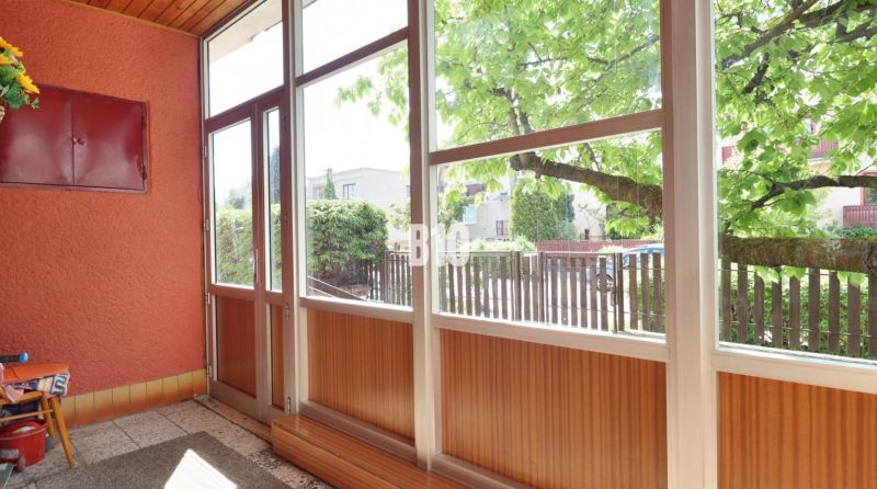 Eine verglaste Veranda mit Blick auf den Hof in einem Einfamilienhaus.
