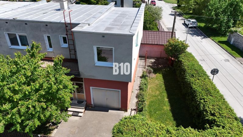 Ein Einfamilienhaus in Martin mit Garten, Garage und Bäumen vor dem Gebäude.