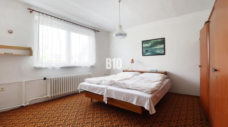 Ein Schlafzimmer in einem Einfamilienhaus mit einem Bett, einem orangefarbenen Teppich und einem Bild an der Wand.