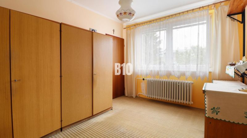 Ein Zimmer in einem Einfamilienhaus mit einem Schrank, Vorhängen und einem Heizkörper.