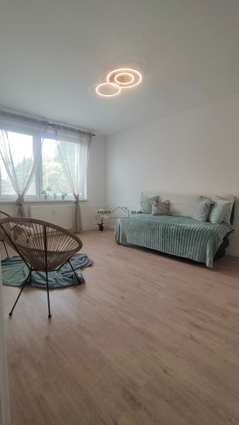 Ein Zimmer in einer 4-Zimmer-Wohnung mit einem Boden in Holzoptik und hellen Möbeln.