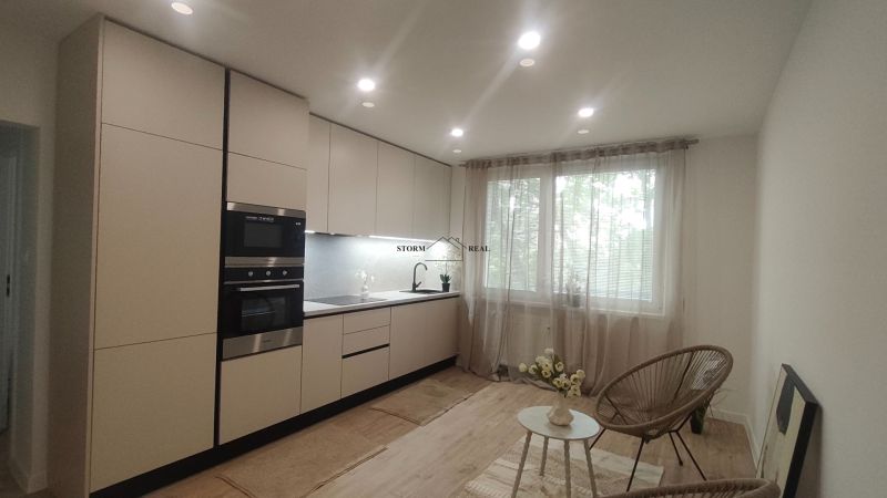 Küche in einer 4-Zimmer-Wohnung mit Holzboden und großem Fenster.