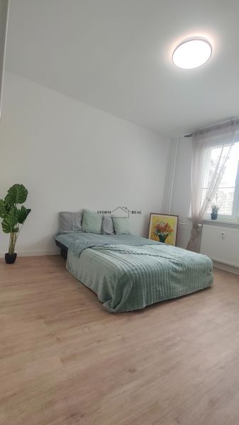 Schlafzimmer in einer 4-Zimmer-Wohnung mit Bett, Pflanze und Holzboden.