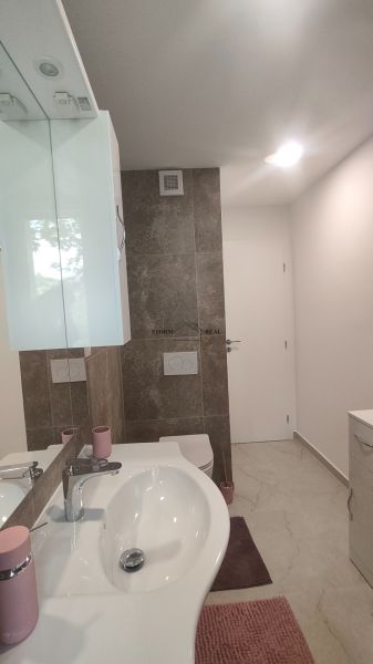 Badezimmer in einer 4-Zimmer-Wohnung mit Waschbecken, Spiegel und Toilette.