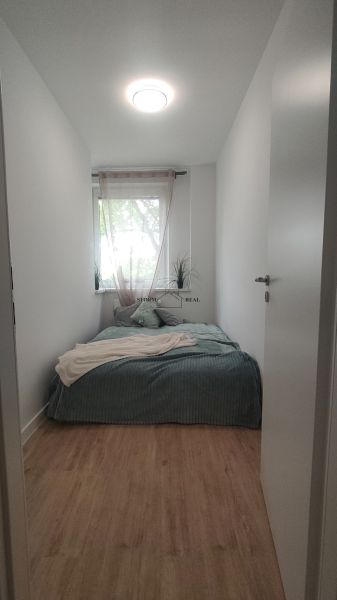 Schlafzimmer mit Bett, weißen Wänden und Boden in Holzoptik in einer 4-Zimmer-Wohnung.