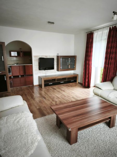 Wohnzimmer in einem Einfamilienhaus mit Sofa, Tisch und Boden in Holzoptik.