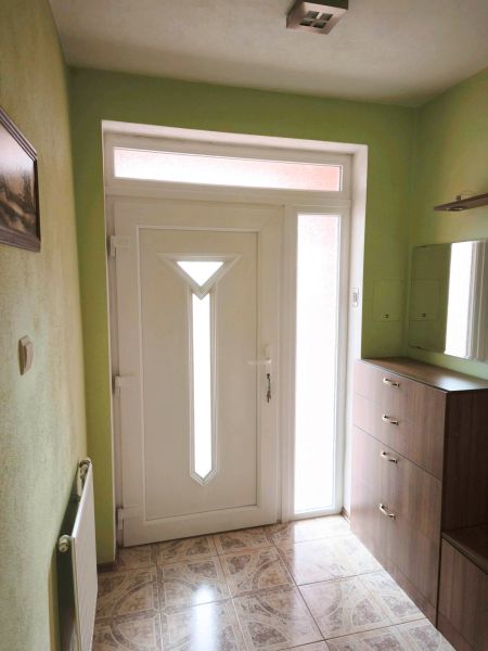 Eingangstür im Einfamilienhaus mit weißem Rahmen und Fliesen mit Dekor.