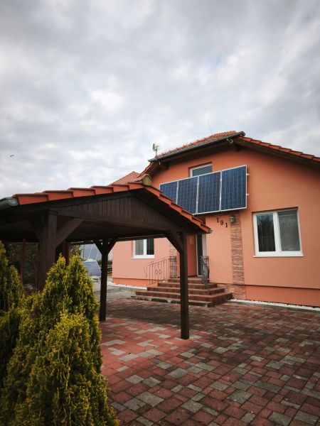 Ein Einfamilienhaus in Martin nad Žitavou mit Solarpaneelen und einem Pavillon auf der Terrasse.