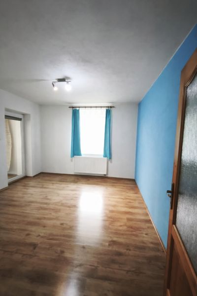 Ein Zimmer in einem Einfamilienhaus mit einer blauen Wand und einem Boden in Holzoptik.