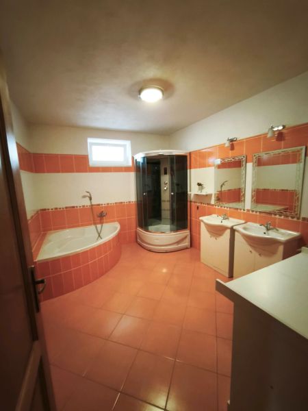 Ein Badezimmer in einem Einfamilienhaus mit orangefarbenen Fliesen, einer Badewanne und einer Dusche.