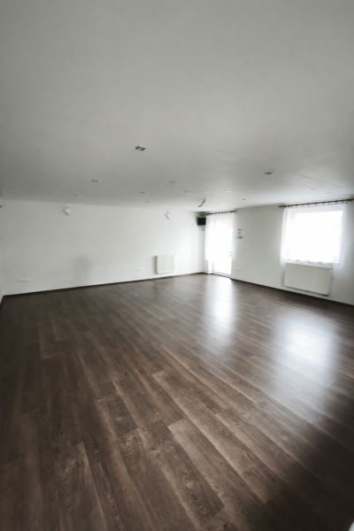 Ein geräumiges Zimmer in einem Einfamilienhaus mit Holzboden und weißen Wänden.