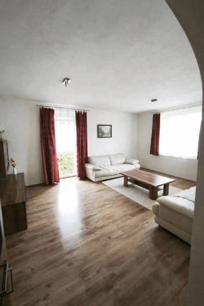 Wohnzimmer in einem Einfamilienhaus mit Sofas, einem Tisch und einem Boden in Holzoptik.
