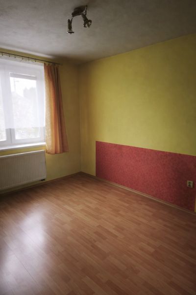 Ein Zimmer in einem Einfamilienhaus mit einem Holzboden und einer farbigen Wand.