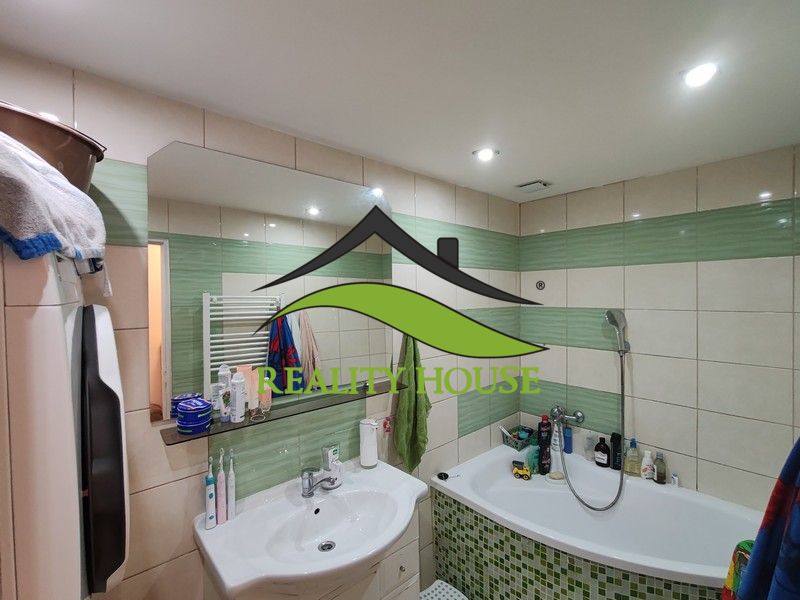 Das Badezimmer einer 3-Zimmer-Wohnung mit Badewanne, Waschbecken und Fliesen in Grüntönen.
