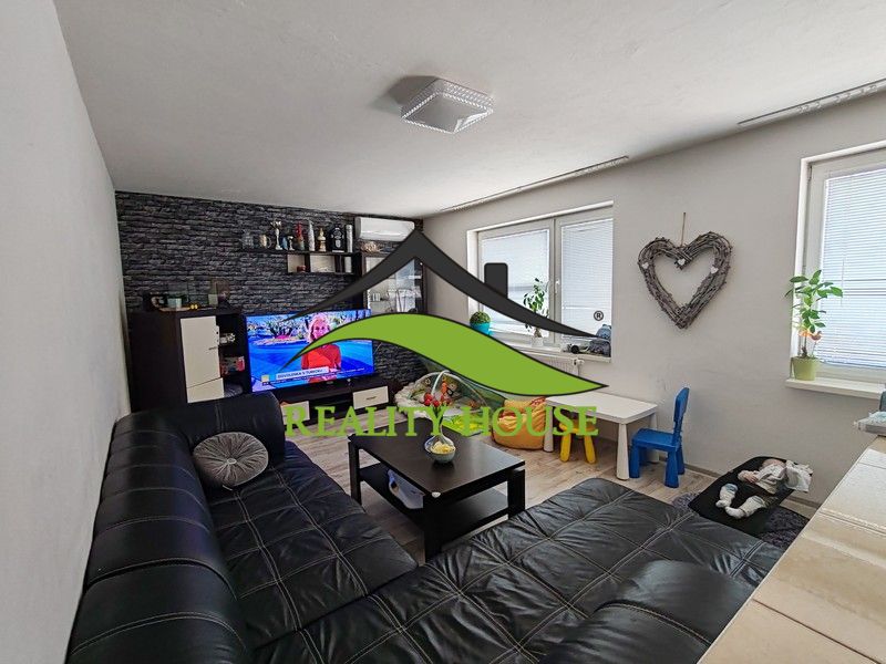Wohnzimmer in einer 3-Zimmer-Wohnung mit Sofa und Fernseher, Boden mit Holzdekor.