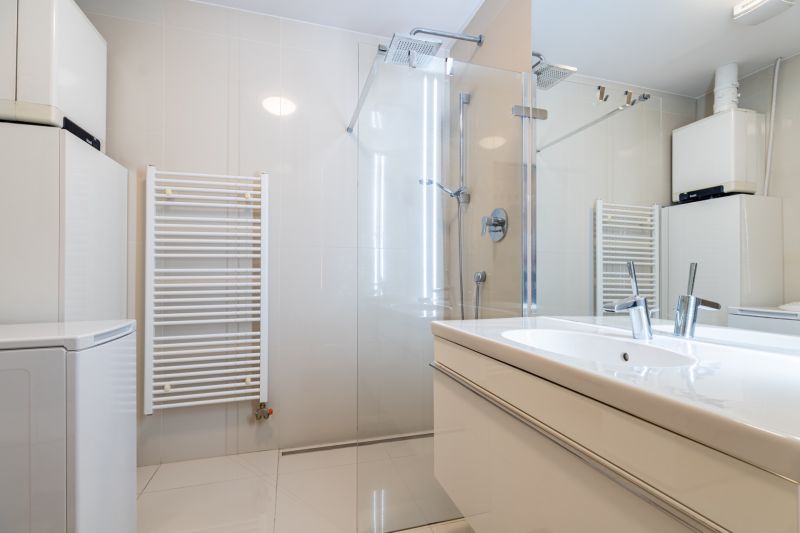Badezimmer in einer 2-Zimmer-Wohnung mit verglaster Duschkabine und Waschbecken.