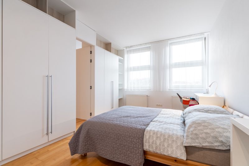Helles Schlafzimmer in einer 2-Zimmer-Wohnung mit Schränken und Bett, Boden mit Holzdekor.