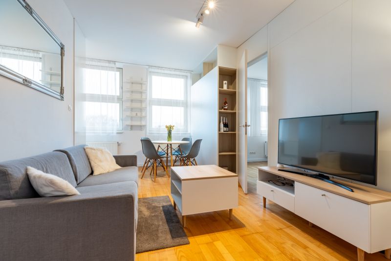 Wohnzimmer mit Holzboden, Sofa und Esstisch in einer Zweizimmerwohnung.