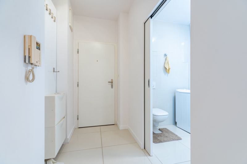 Flur in einer 2-Zimmer-Wohnung mit Gegensprechanlage, Schrank und eingebautem WC mit hellen Fliesen.
