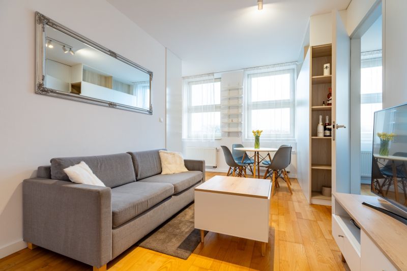 Wohnzimmer in einer Zweizimmerwohnung mit Sofa, Tisch und Holzboden.