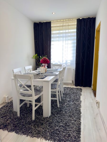 Esszimmer mit grauem Teppich und weißen Möbeln in einer 4-Zimmer-Wohnung.