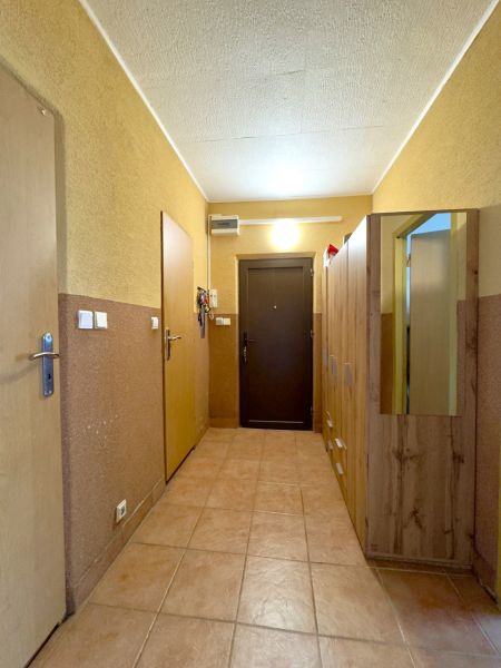 Ein Flur mit Schränken in einer 4-Zimmer-Wohnung mit Fliesenboden und Holztüren.