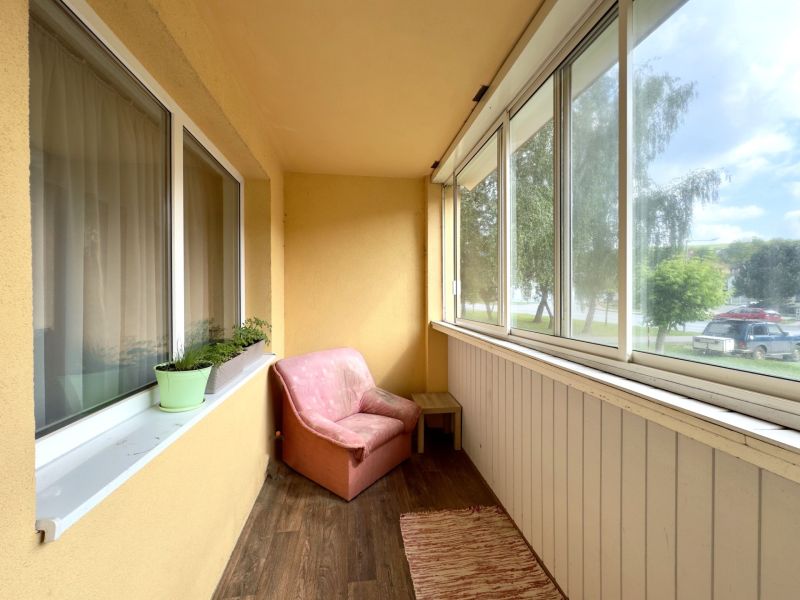 Balkon einer 4-Zimmer-Wohnung mit Sitzgelegenheit und Boden in Holzoptik.