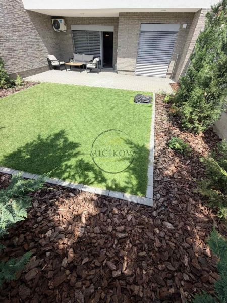 Der Garten einer 2-Zimmer-Wohnung in Galanta mit Rasenfläche und Terrassensitzbereich.