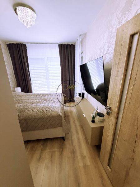 Schlafzimmer in einer 2-Zimmer-Wohnung mit Holzboden und einem Fernseher an der Wand.