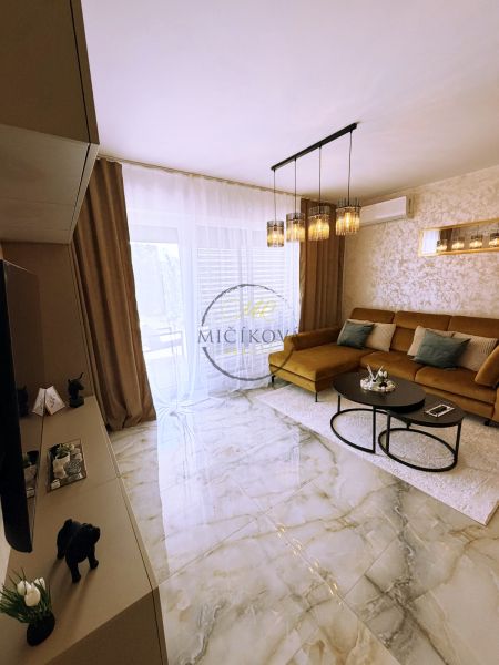 Wohnzimmer in einer 2-Zimmer-Wohnung mit glänzenden Fliesen und einem Sofa.