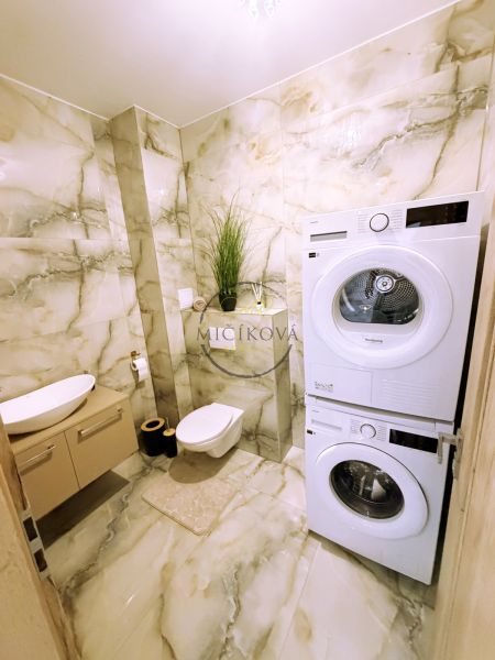 Badezimmer mit Waschmaschine und Trockner in einer 2-Zimmer-Wohnung mit Marmorverkleidung.