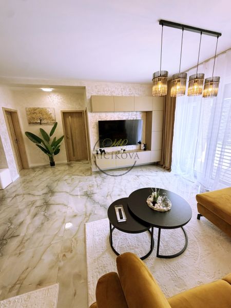 Wohnzimmer in einer Zweizimmerwohnung mit Marmorboden und stilvoller Beleuchtung.