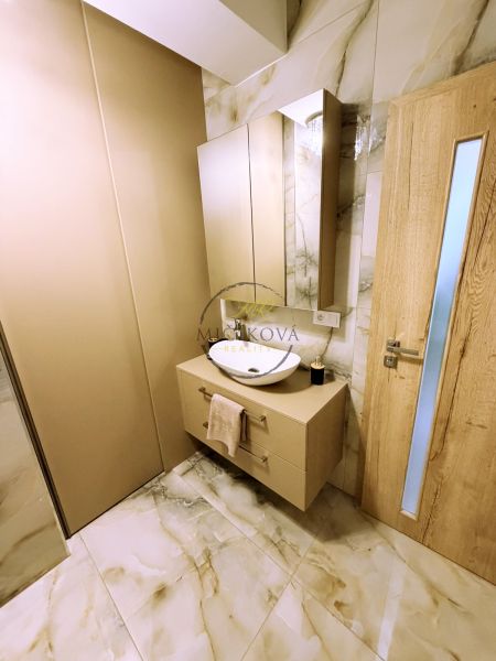 Badezimmer mit Schrank und Waschbecken, Fliesen mit Marmormuster, Holztüren.