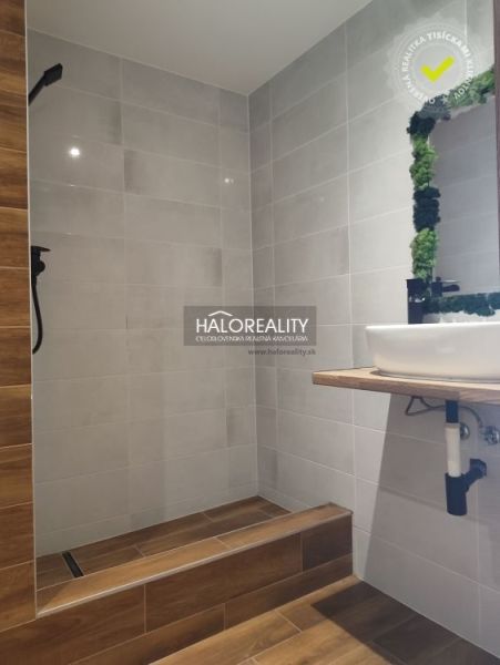 Badezimmer in einer Einzimmerwohnung mit Holzboden und hellen Fliesen.