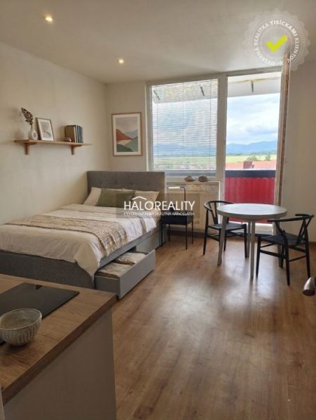 Einzimmerwohnung mit großem Fenster, Bett, Tisch und Boden in Holzoptik.