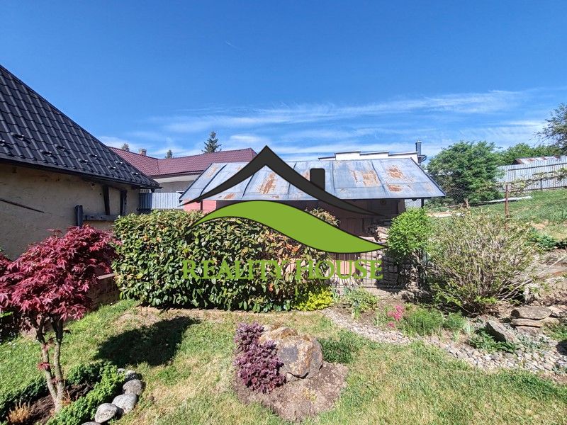 Ein Einfamilienhaus in der Hauptstraße in Banské mit einem gepflegten Garten und blauem Himmel.