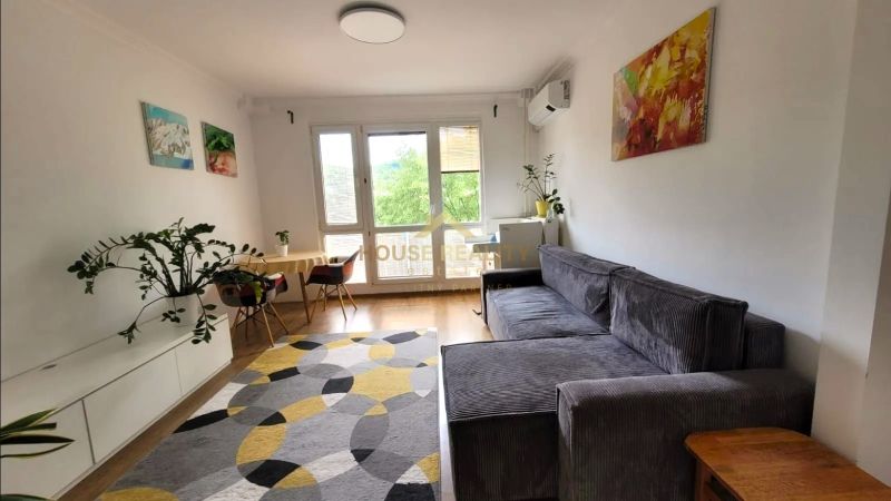 Wohnzimmer mit Sofa in einer 3-Zimmer-Wohnung mit Holzboden und Dekorationen.
