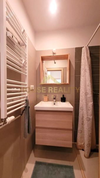 Badezimmer mit Holzdekor in einer 3-Zimmer-Wohnung, Waschbecken, Spiegel, Duschkabine.
