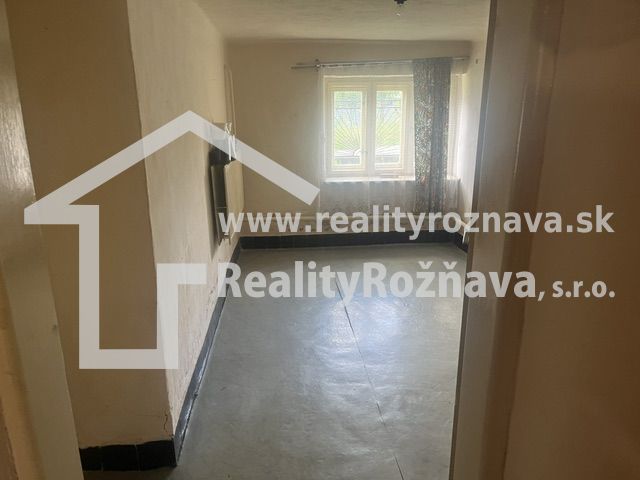Ein Zimmer in einem Einfamilienhaus mit Betonboden und einem Fenster mit einfallendem Licht.