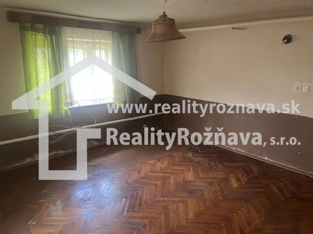 Ein Zimmer in einem Einfamilienhaus mit einem Holzboden und grünen Vorhängen.