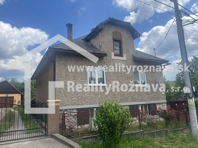 Ein Einfamilienhaus in Rudná mit einer zweistöckigen Fassade, einem eingezäunten Grundstück und blauem Himmel.