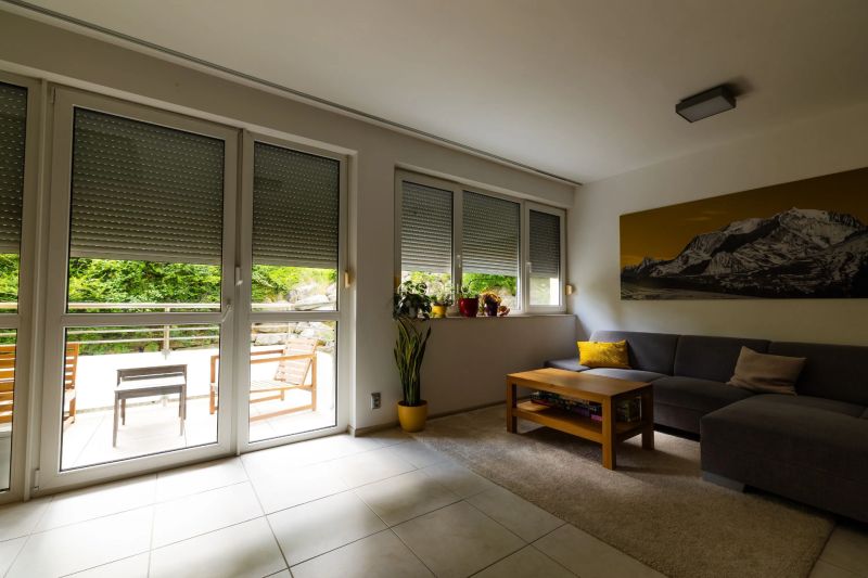 Wohnzimmer in einer 2-Zimmer-Wohnung mit Sofa, Tisch und Blick auf die Terrasse.