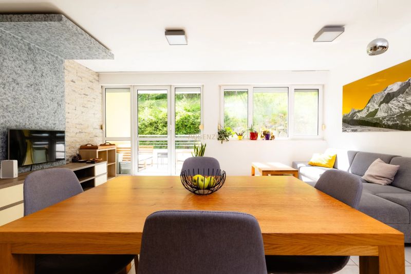 Wohnzimmer in einer Zweizimmerwohnung mit Holztisch und Sofa, Blick auf die Terrasse.