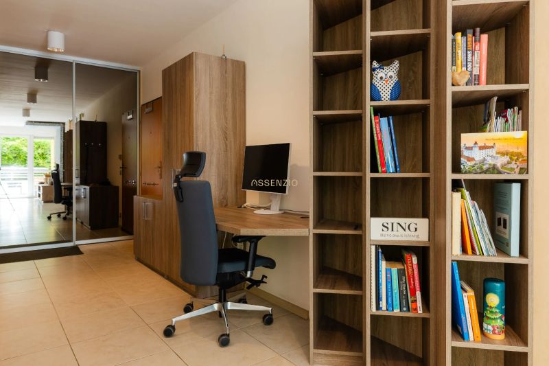 Bücherschrank und Arbeitsecke mit Stuhl in einer 2-Zimmer-Wohnung mit Blick auf den Balkon.